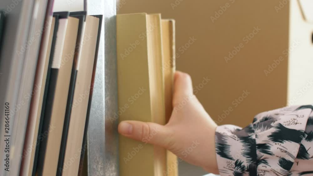 Close up of woman hand puts book on shelf. 4k slow motion footage. 4k.