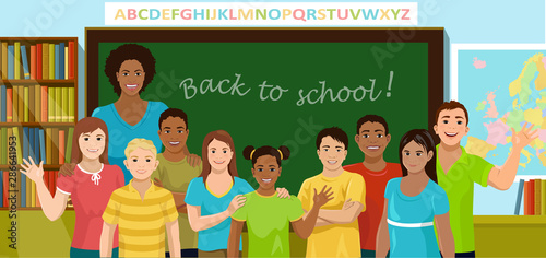 Teacher and pupils are in the schoolroom. African American teacher and children of different ethnicity stand in front of the blackboard, bookcase and map. Back to school concept. Vector illustration.