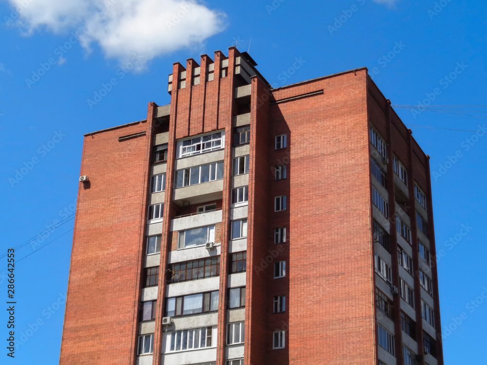 Soviet architecture. Ust-Kamenogorsk (Kazakhstan). Apartment building. Soviet architectural style. Typical socialist apartment building. Apartment block. Blue sky and red brick