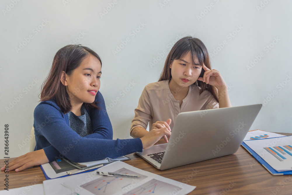Two young ladies working on laptop and financial paperworks Two young ladies working on laptop and financial paperworks