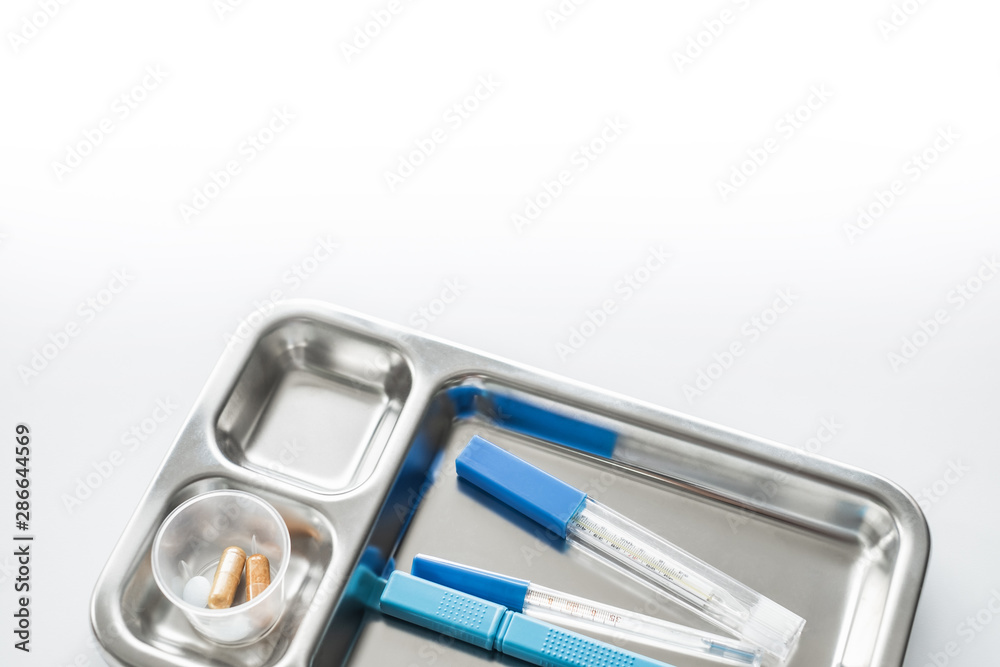 Metal tray with thermometers and pill bottle on white background Metal tray with thermometers and pill bottle on white background