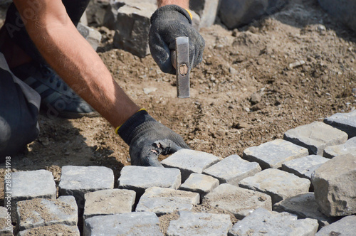 worker stacks paving stones