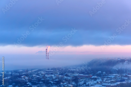 evening landscape of a winter industrial zone with smoking chimneys