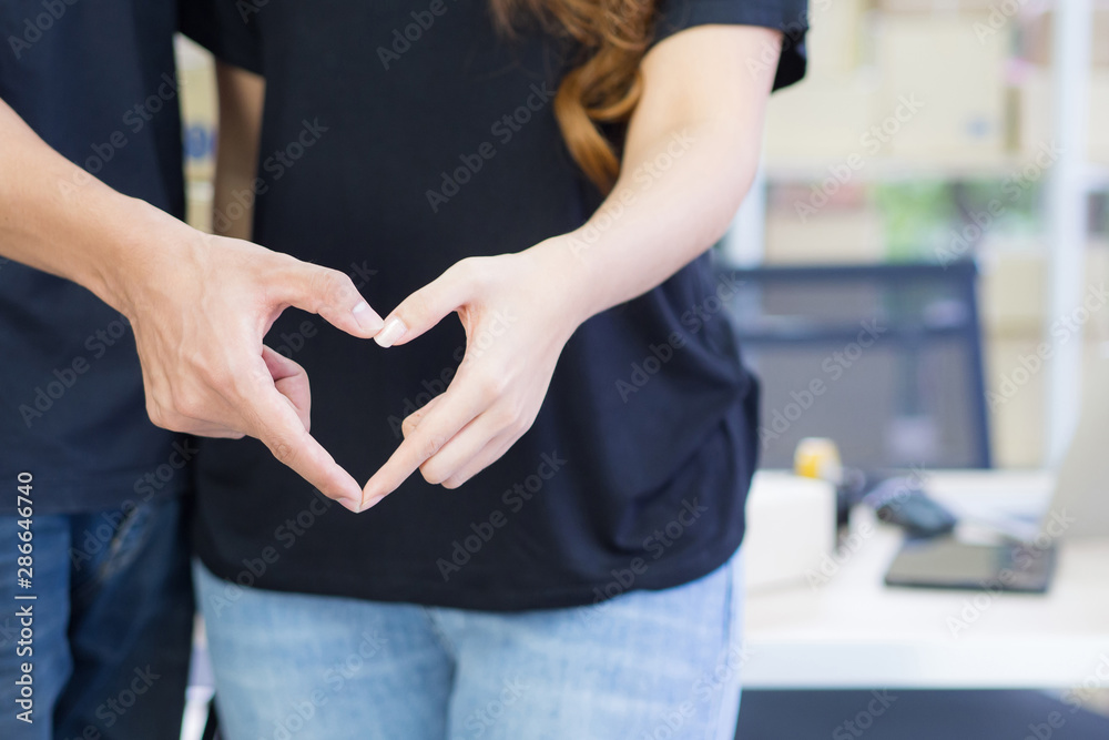 Young couple making heart shape with hands with space for text