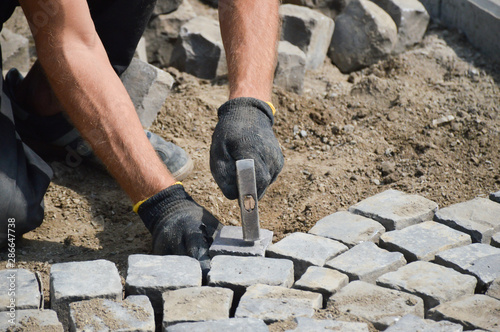 worker stacks paving stones