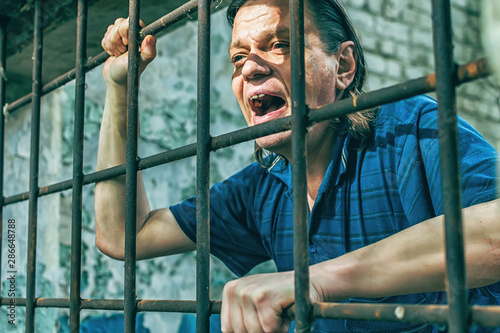 Foto A depressed man in handcuffs behind bars