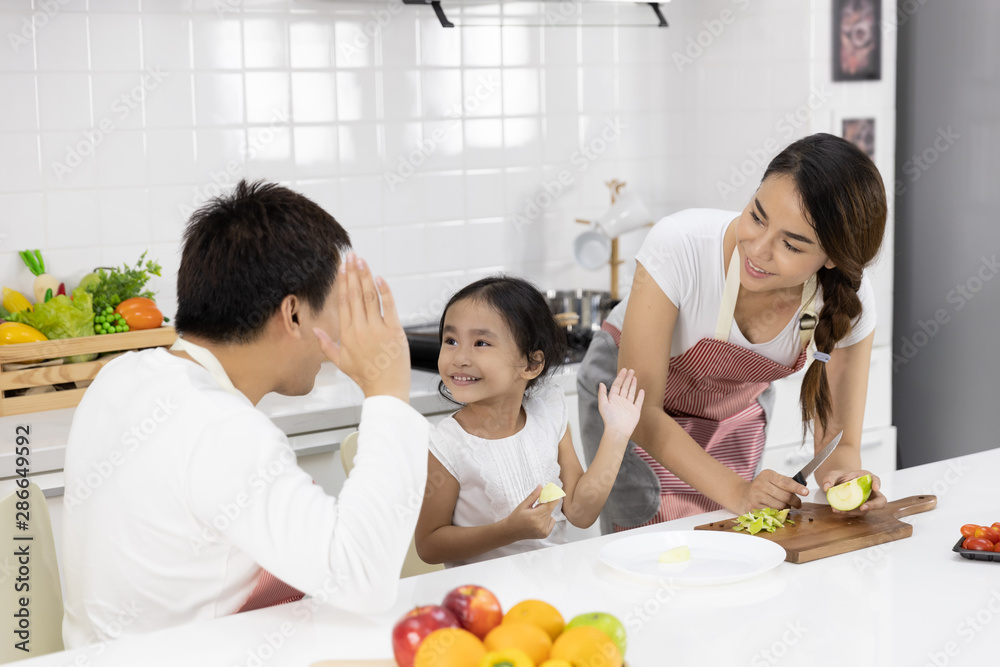 Happy Asian family make a cooking. Father, Mother and Daughter are preparing fruit, green apple in the kitchen at home. Healthy food concept and happy holidays Happy Asian family make a cooking. Father, Mother and Daughter are preparing fruit, green apple in the kitchen at home. Healthy food concept and happy holidays