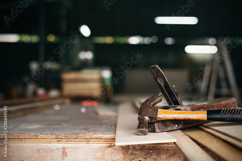 old vintage hammers and hallmark steel punches on a rustic wooden workbench of a goldsmith against a dark background,