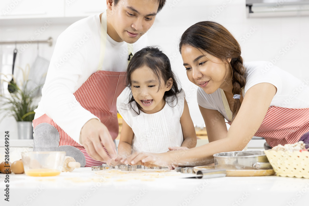 Happy Asian family Father, Mother and Daughter are preparing the dough, bake cookies in the kitchen in home. family cooking food Concept. Happy Asian family Father, Mother and Daughter are preparing the dough, bake cookies in the kitchen in home. family cooking food Concept.