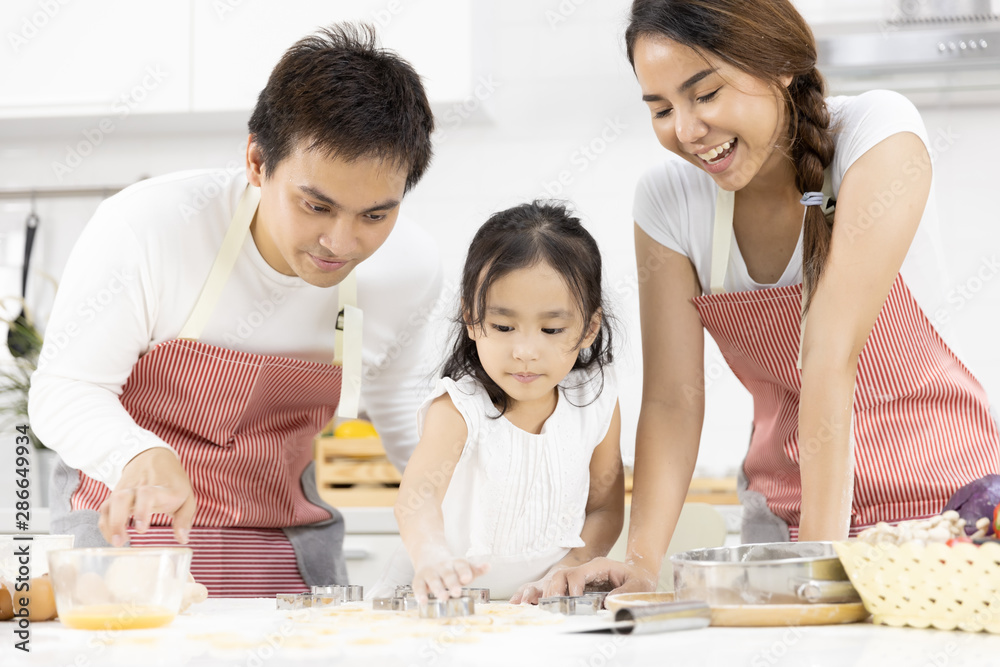 Happy Asian family Father, Mother and Daughter are preparing the dough, bake cookies in the kitchen in home. family cooking food Concept. Happy Asian family Father, Mother and Daughter are preparing the dough, bake cookies in the kitchen in home. family cooking food Concept.