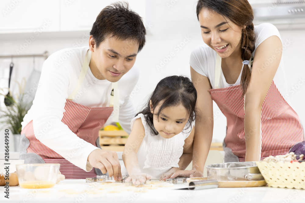 Happy Asian family Father, Mother and Daughter are preparing the dough, bake cookies in the kitchen in home. family cooking food Concept. Happy Asian family Father, Mother and Daughter are preparing the dough, bake cookies in the kitchen in home. family cooking food Concept.