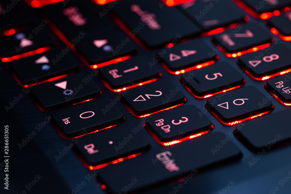 Red backlit laptop keyboard. Close-up.