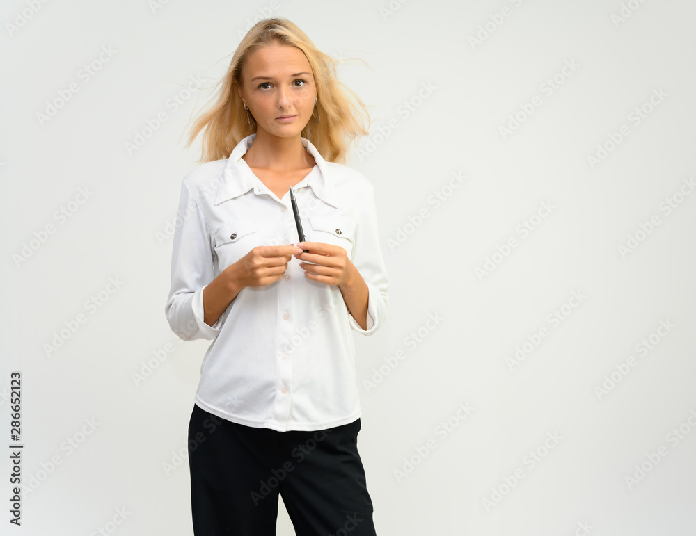 Studio portrait of a pretty blonde student girl, young woman in a white shirt on a white background. Talking, showing emotions.