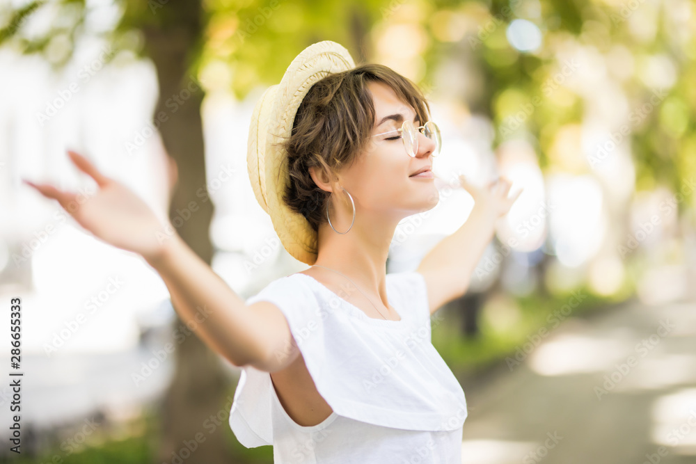 Enjoying the nature. Young woman with straaw hat arms raised enjoying the fresh air in green forest. Enjoying the nature. Young woman with straaw hat arms raised enjoying the fresh air in green forest.