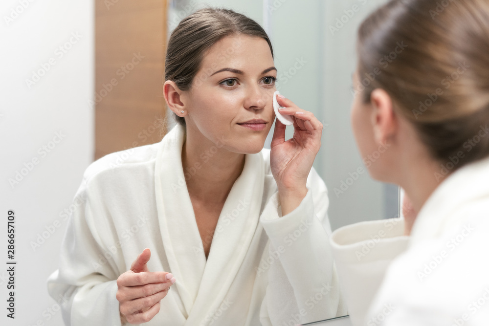 Woman in white bathrobe holding cotton pad in hands Woman in white bathrobe holding cotton pad in hands