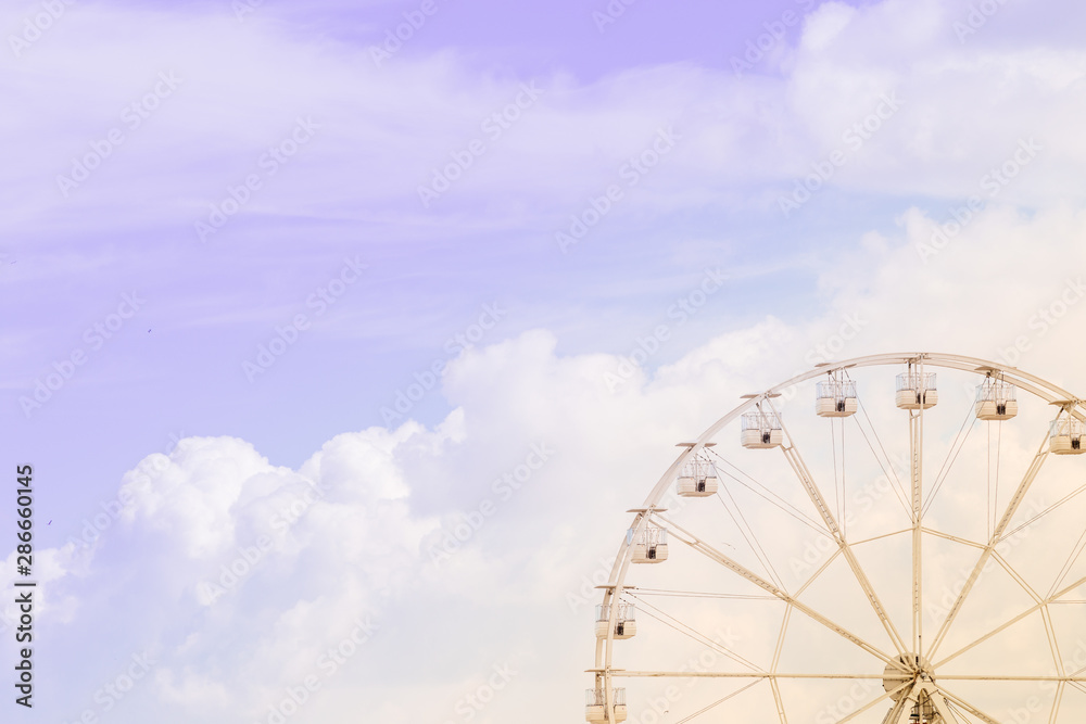 Ferris wheel on the colorful cloudy sky. Background concept of happy holidays time.