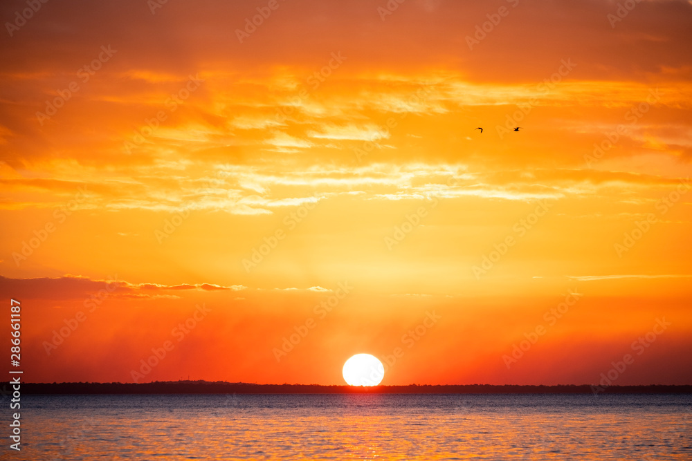 Orange ball of sun at sunset from Fraser Island, Queensland, Australia