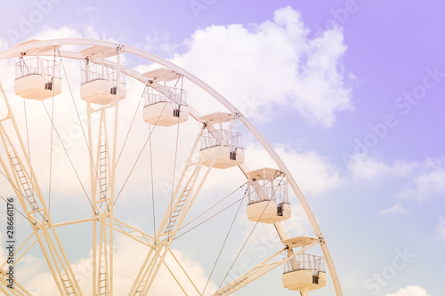 Ferris wheel on the colorful cloudy sky. Background concept of happy holidays time. © sergiymolchenko