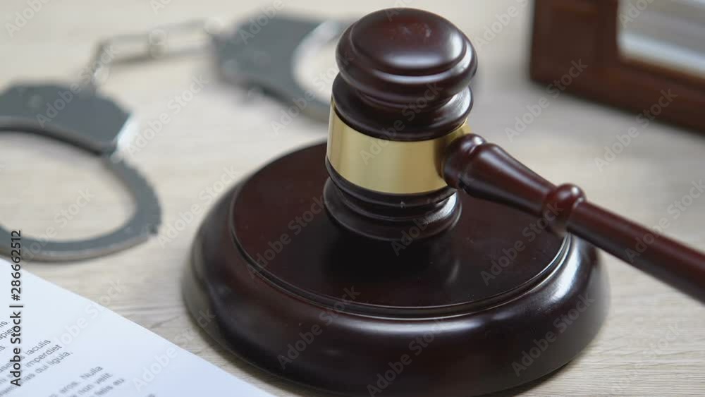 Handcuffs on table, judge hitting gavel once, putting criminal in jail, court Handcuffs on table, judge hitting gavel once, putting criminal in jail, court