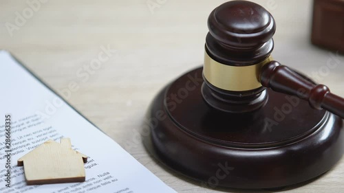 Wooden house on table, judge hitting gavel, real estate affair, court verdict photo