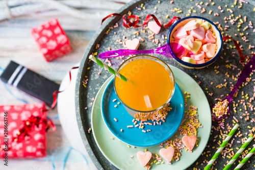 flat lay of birthday party scene with orange juice, ribbon, candy, presents