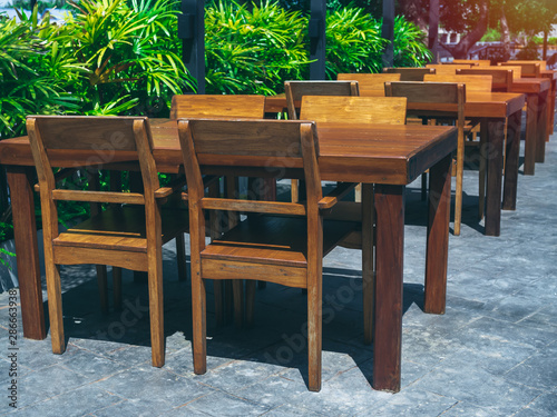 Wooden dining table set near the green garden.