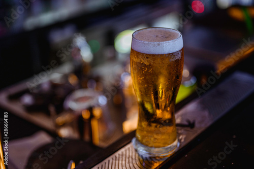 Fototapeta Glass of light beer on a bar.