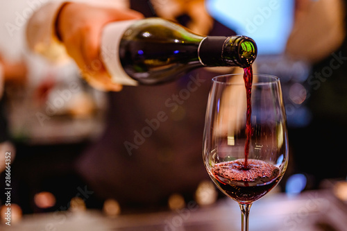 Pouring glass of red wine from a bottle. Fototapete