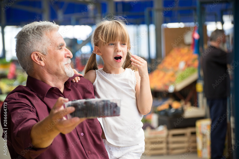 Granddaughter and grandfather buying at the green market Granddaughter and grandfather buying at the green market