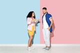 Young emotional caucasian couple in bright casual clothes posing on pink and blue background. Concept of human emotions, facial expession, relations, ad. Woman angry talking to man, he's sad.