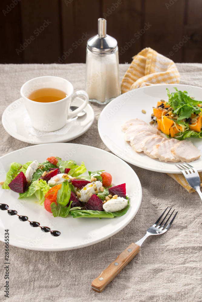 lunch set beetroot cheese salad and roasted turkey fillet with pumpkin and cup of green tea on the table