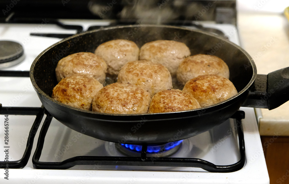 Pork cutlets are fried in a pan on a gas stove. Pork cutlets are fried in a pan on a gas stove.
