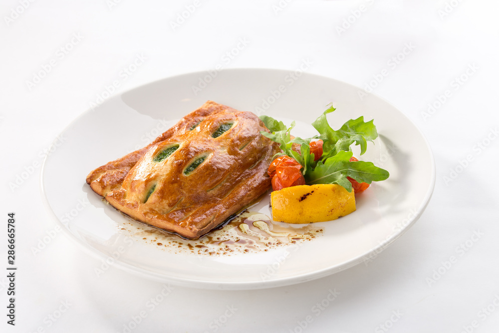Puff pastry bun with spinach and tomato and lemon on the side isolated on white background