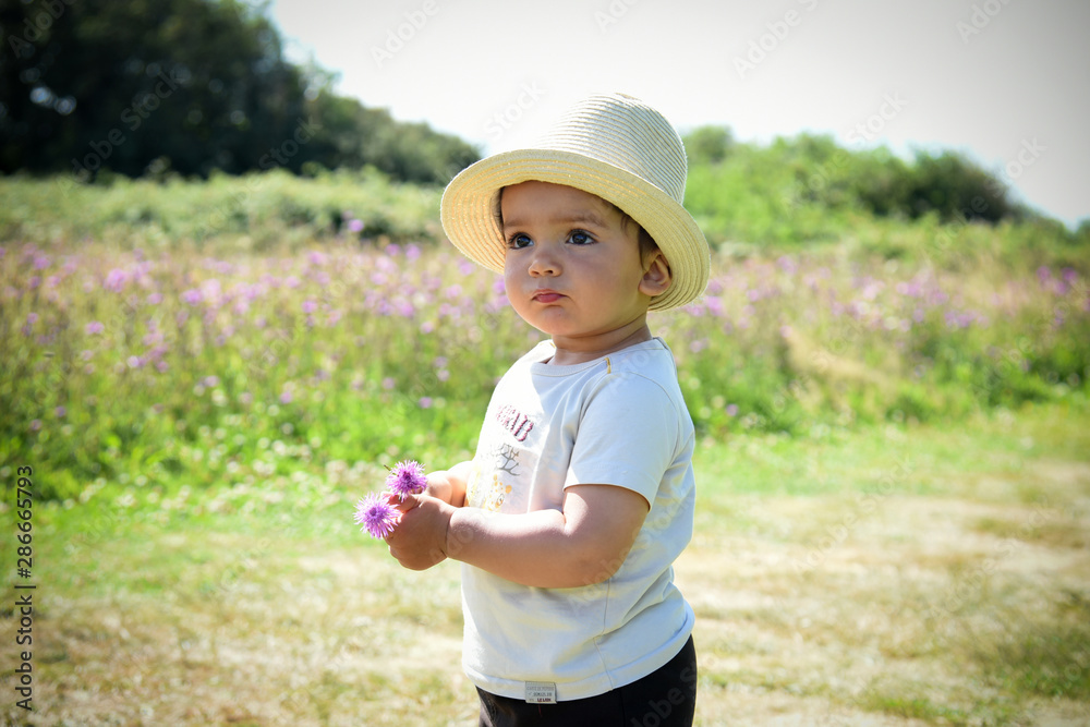 Jeune garçon cueillant une fleur dans un champs Jeune garçon cueillant une fleur dans un champs