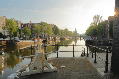 Sint Antoniesluis lock, overlooking Oudeschans canal, with reflections. Picture taken early morning with sun rays and sun star, Amsterdam, Netherlands photo