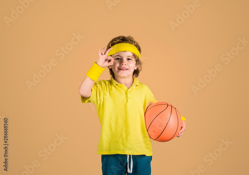 Fototapeta Naklejka Na Ścianę i Meble -  Enjoy sport game. Cute boy playing basketball. Child boy in sportswear holds ball. Basketball training. Active sports lifestyle. Sport game. Kid activities. Little basketballer. Sports equipment.