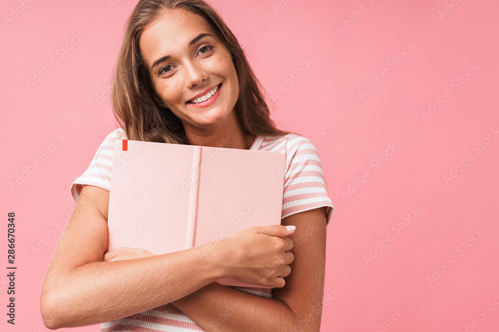 Image closeup of young pretty woman smiling at camera while hugging her diary book