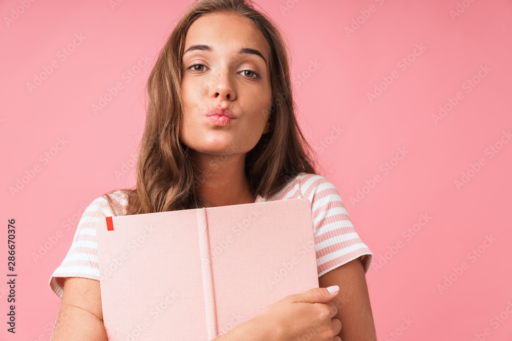 Image closeup of alluring pretty woman making kiss at camera while hugging her diary book Image closeup of alluring pretty woman making kiss at camera while hugging her diary book
