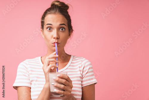 Image closeup of surprised young woman expressing wonder and drinking chocolate milk with straw