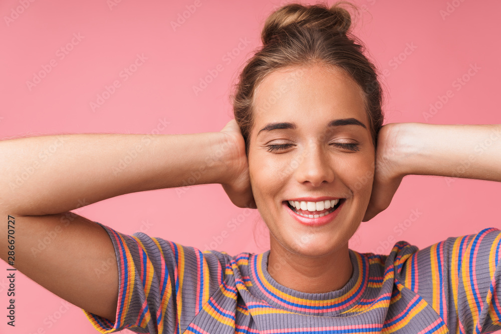 Image closeup of cheerful beautiful woman smiling and covering her ears with hands Image closeup of cheerful beautiful woman smiling and covering her ears with hands