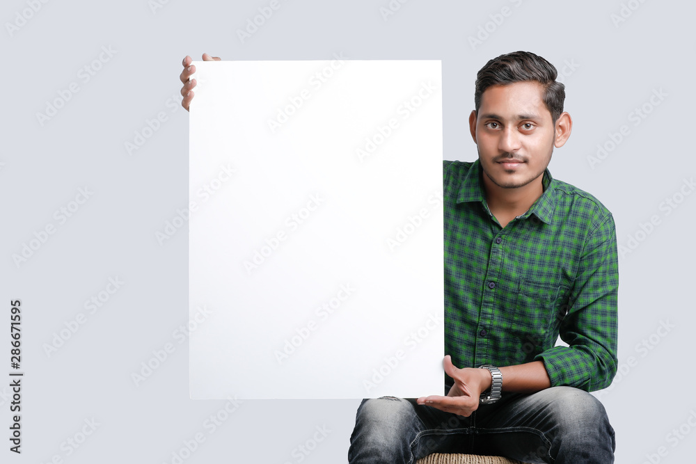 young indian guy holding blank poster - obrazy, fototapety, plakaty 