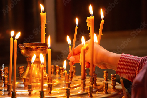 Woman hand picking candle in church, traditional religious scene photo