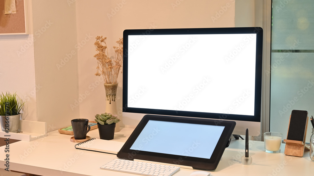 Fototapeta premium Mockup tablet and computer on creative workspace with warm light.