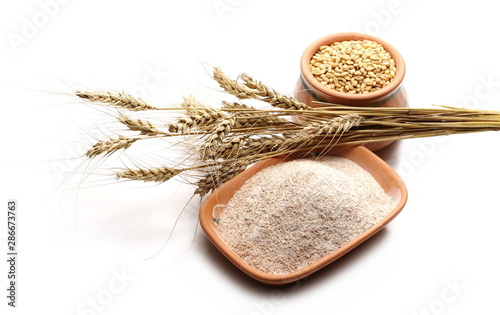 Wheat grains, ears, and integral flour in clay pot isolated on white background 