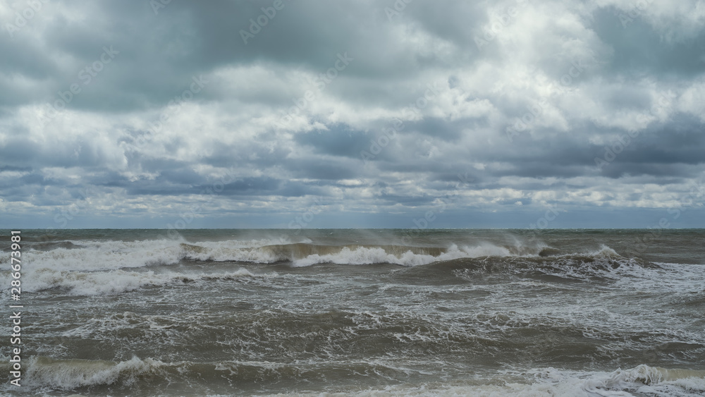 sea waves, windy weather against a cloudy cloudy sky.