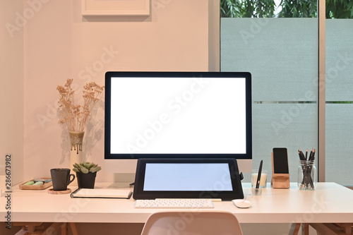 Mockup tablet and computer on creative workspace with warm light.