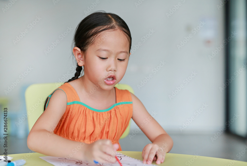 Adorable little Asian girl drawing and painting with water color on paper in children room Adorable little Asian girl drawing and painting with water color on paper in children room