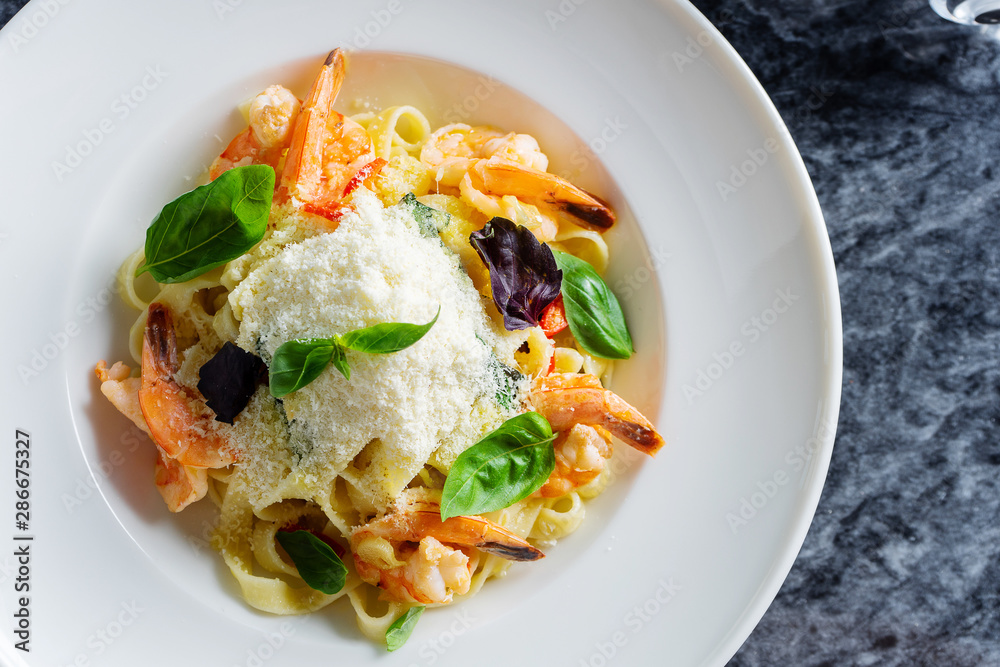 Top view pasta with seafood, shrimp, basil, and parmesan on marble table. Spaghetti in a white bowl. Traditional Italian cuisine. Copy space. Selective focus. Food photography Top view pasta with seafood, shrimp, basil, and parmesan on marble table. Spaghetti in a white bowl. Traditional Italian cuisine. Copy space. Selective focus. Food photography
