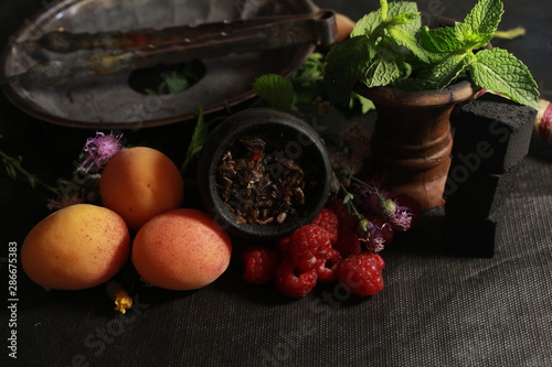 Fototapeta Naklejka Na Ścianę i Meble -  bowl with tobacco for hookah. fruits on a dark background. smoking shisha
