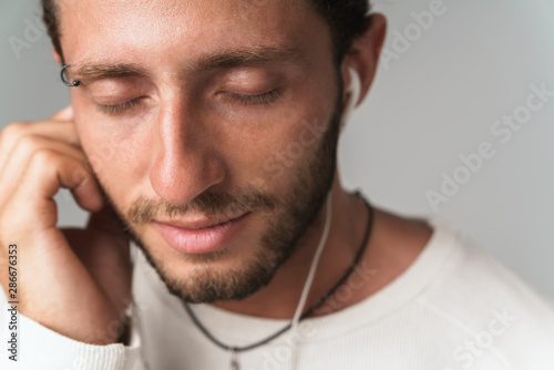 Close up of a smiling young man enjoys listening to music